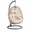 Sillón colgante de ratán sintético con cojines beige y estructura metálica
