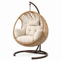 Sillón colgante de ratán con estructura de acero y cojines crema